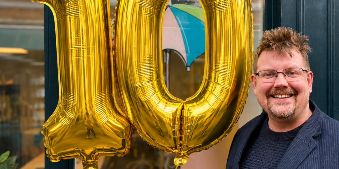 Kevin holding golden balloons in the shape of a 1 and 0