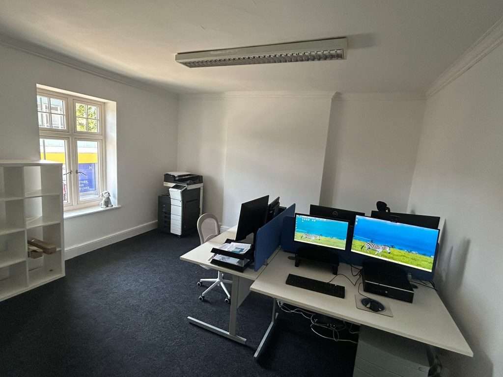 Photo of our new office – a group of three desks with dark grey carpet 