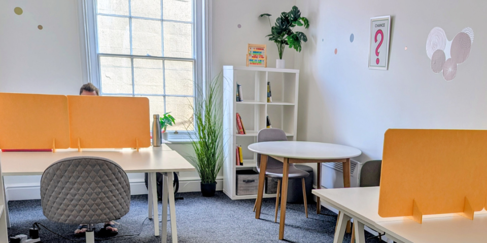 Picture of our hot desking room with Ascentant's logo and the testimonial on top.